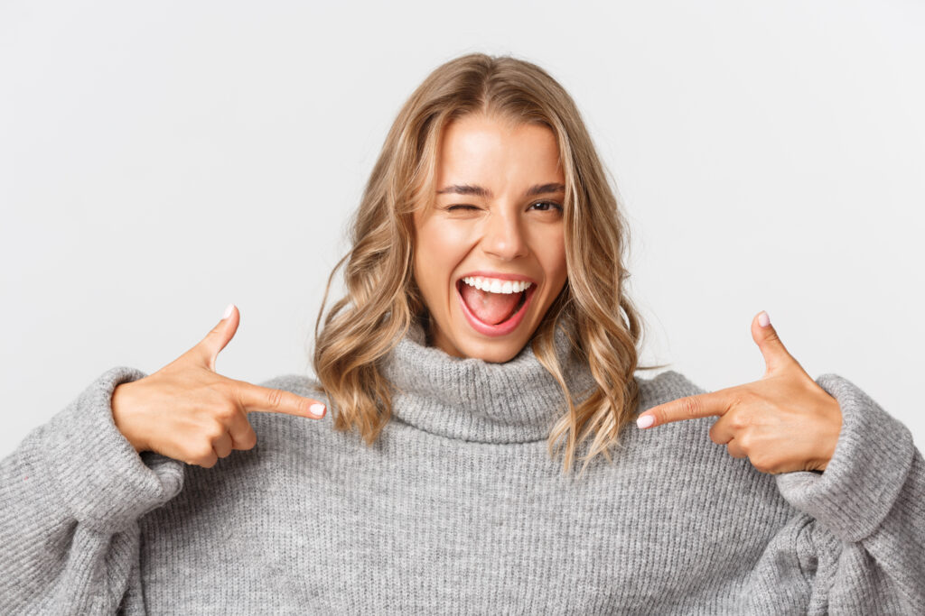Smiling woman pointing at her confident smile